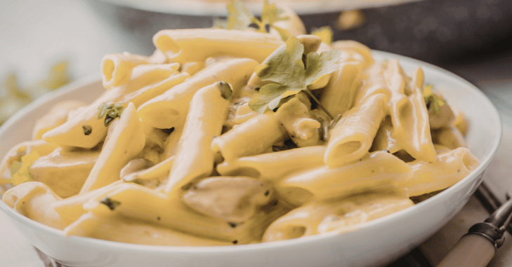 Dry penne pasta poured onto a wooden board