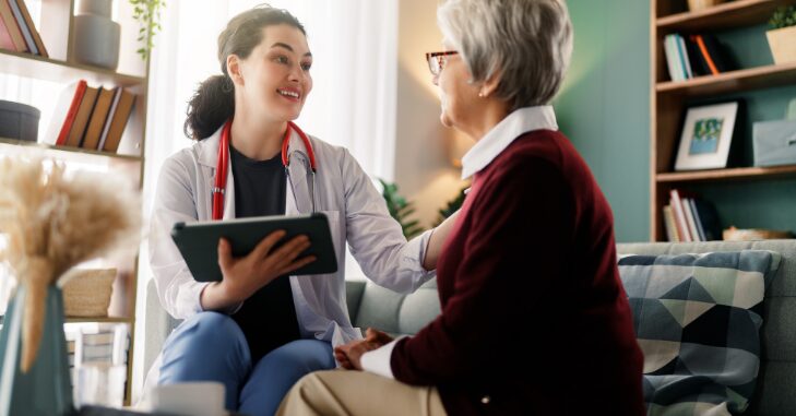Caregiver assisting a senior in a nursing home hallway
